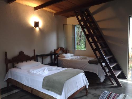 two beds in a room with a staircase at Pousada Éden in Sao Jorge