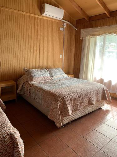 a bedroom with a bed and a window and a fan at Cabañas Bosque Sur in Puerto Varas