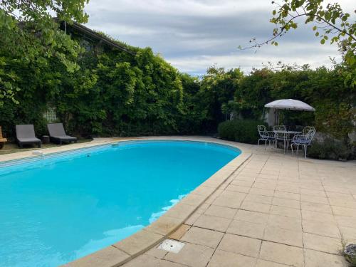 une piscine avec une table, des chaises et un parasol dans l'établissement Gorgeous 5 Bed French Farmhouse, à Eymet