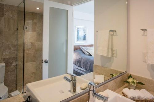 een badkamer met een wastafel, een douche en een spiegel bij SUPERMODERNO En Pleno Centro Histórico in Mexico-Stad