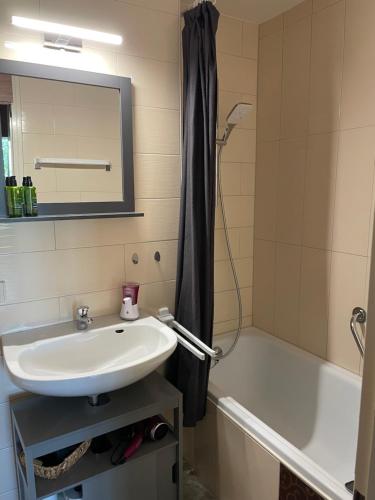 ein Badezimmer mit einem Waschbecken, einer Badewanne und einem Spiegel in der Unterkunft Ferienwohnung Bergblick in Füssen
