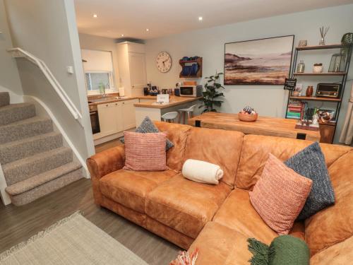 a living room with a brown couch and a kitchen at Dodds Nook in Alnwick