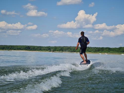 a man riding a wave on a surfboard in the water at Luxusferienhaus Seevilla Monaco am Fleesensee in Göhren-Lebbin