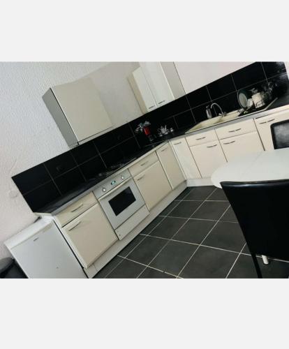 a kitchen with white cabinets and a black tile floor at Beau studio lumineux à 2mn à pied du tramway. 