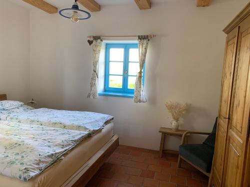 a bedroom with a bed and a window and a chair at Roubenka Kokořínsko in Dubá