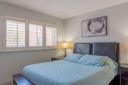 um quarto com uma cama azul e 2 janelas em Amazing water front view home newly renovated 3BD 2BTH em Clearwater Beach