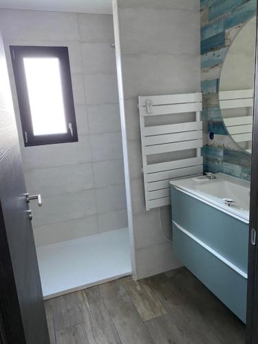 une salle de bain avec une baignoire, un lavabo et un miroir dans l'établissement L'Offshore, à Penmarcʼh