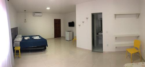 a bedroom with a blue bed and yellow chairs at Solar da Praia Pousada in Arraial do Cabo