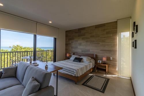 1 dormitorio con cama, sofá y balcón en Ocean View Loft - Punta Cocos en Holbox Island