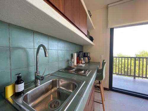 une cuisine avec un évier en acier inoxydable et une fenêtre dans l'établissement Ocean View Loft - Punta Cocos, à Holbox