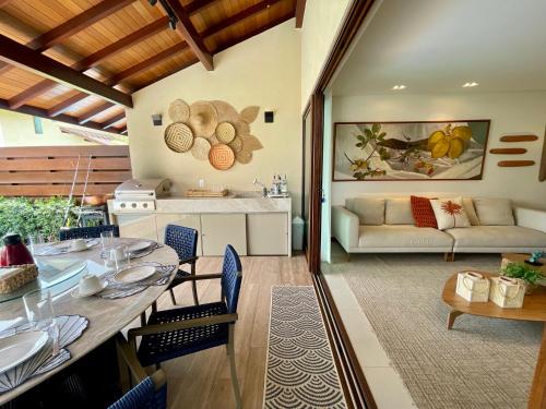 uma cozinha e sala de estar com uma mesa e um sofá em Casa Luxo com piscina privativa próximo a Igrejinha - Com colaboradora e enxoval em Praia dos Carneiros
