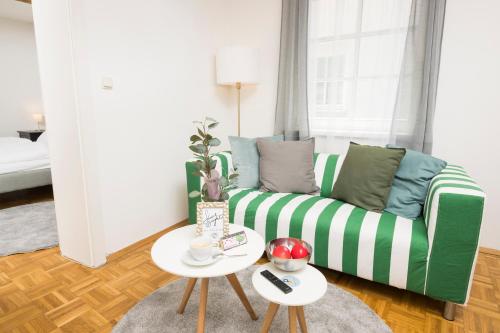 a living room with a green couch and two tables at Zum Grazer Uhrturm in Graz