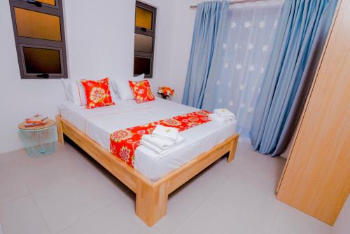 a bedroom with a bed with red pillows and blue curtains at L'Etoile in Flic-en-Flac