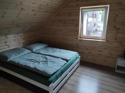 Cama en habitación de madera con ventana en Domek na Blejchu, en Wisła
