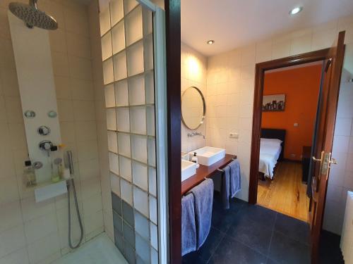 Un baño con ducha, lavabo y espejo. en Teo, en Pamplona