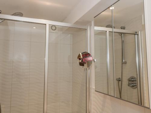 a shower with a glass door and a mirror at Greystones in Newton Stewart