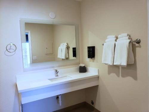 a bathroom with a sink and a mirror and towels at Hotel Avisa Downtown in Morro Bay