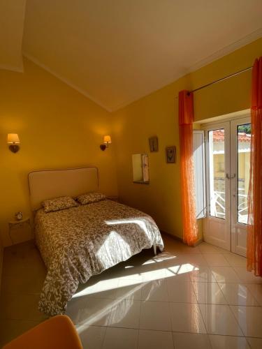Dormitorio amarillo con cama y ventana en Maison chaleureuse avec piscine et spa, en Vale de Cambra