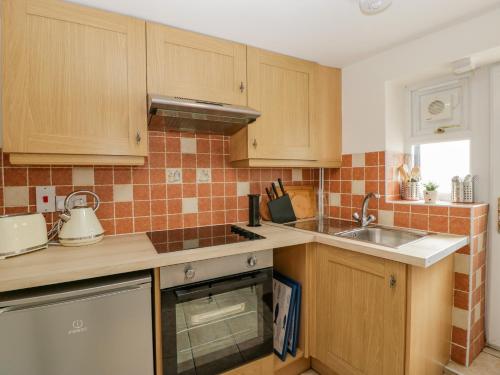 a kitchen with wooden cabinets and a sink at The Cwtch in Abergavenny