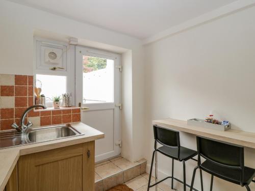 a kitchen with a sink and two bar stools at The Cwtch in Abergavenny