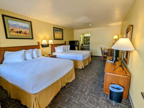 a hotel room with two beds and a television at Best Western Executive Inn in Hallettsville