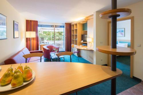 ライプツィヒにあるスイート ホテル ライプチヒのテーブルとフルーツの盛り合わせが備わる部屋