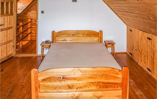 a bed in a room with wooden walls and wooden floors at Stunning Home In Biskupiec With 4 Bedrooms And Wifi in Biesówko