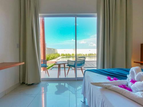 a bedroom with a bed and a view of the ocean at Caly Pousada in São Miguel do Gostoso