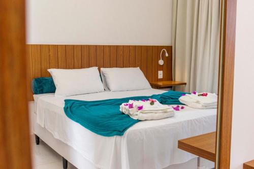 a bedroom with a bed with two towels on it at Caly Pousada in São Miguel do Gostoso