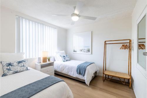a white bedroom with two beds and a mirror at Thurlow Lodge, 7,6 Thurlow Avenue - Beautifully styled unit with WiFi, views and a pool in Nelson Bay