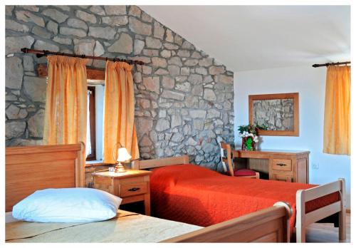 a bedroom with two beds and a stone wall at Villa Calussovo in Ripenda Kras