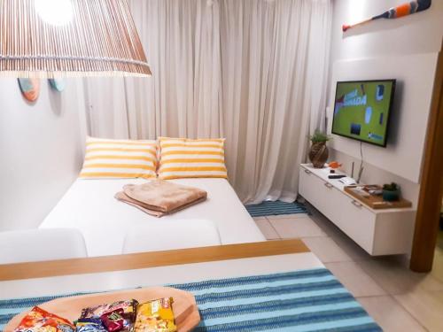 a bedroom with a white bed and a television at Porto de Galinhas - Flat com Piscina Exclusiva in Porto De Galinhas