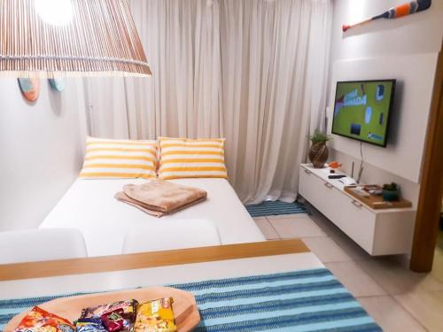 a bedroom with a white bed and a television at Flat em Porto de Galinhas com Piscina Exclusiva in Porto De Galinhas