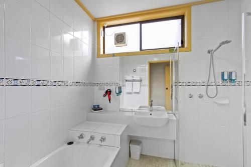 a white bathroom with a tub and a sink at Emmanuel Holiday Apartment in Lakes Entrance