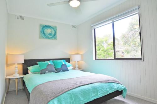 a bedroom with a large bed with a window at GUMNUT COTTAGE - FREE WIFI & FOXTEL in Inverloch