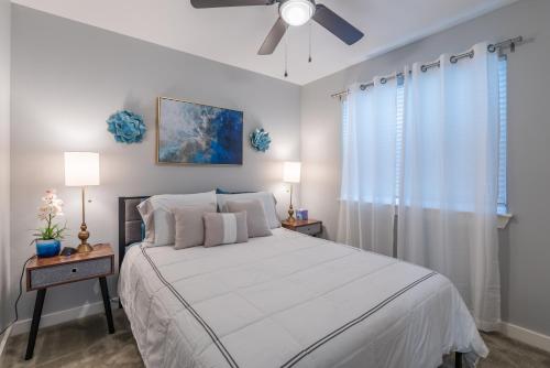 Un dormitorio con una cama blanca y un ventilador de techo. en Eastlawn Place cozy 2 bdrm townhome near downtown San Antonio, en San Antonio
