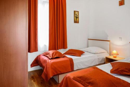 two beds in a room with orange curtains at Apartments with a parking space Bol, Brac - 20004 in Bol