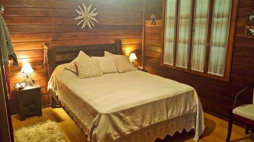 sypialnia z łóżkiem w pokoju z drewnianymi ścianami w obiekcie Chalé Canoas - Conforto na serra de Teresópolis w mieście Teresópolis