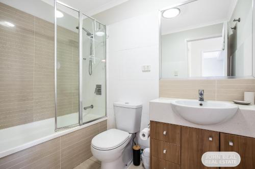 a bathroom with a white toilet and a sink at Suttons Beach Apartments in Redcliffe