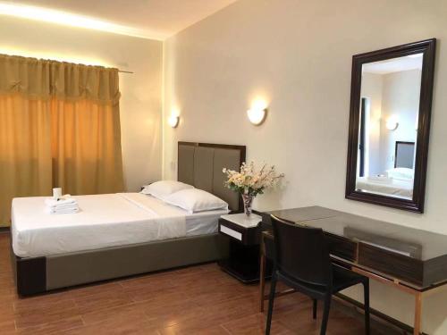sypialnia z łóżkiem i biurkiem z lustrem w obiekcie Meaco Royal Hotel- Aparri w mieście Camalaniugan