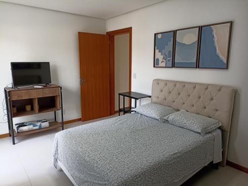 a bedroom with a bed and a flat screen tv at Flat Santa Cruz II in Santa Cruz do Sul