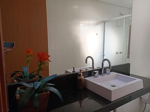 W łazience znajduje się biała umywalka i lustro. w obiekcie Flat Santa Cruz II w mieście Santa Cruz do Sul
