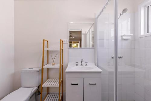 a white bathroom with a sink and a shower at Spring Cottage in Nowra