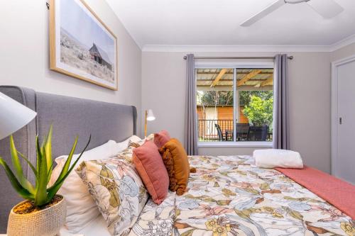 a bedroom with a bed with a plant and a window at Spring Cottage in Nowra