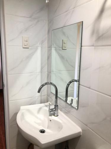 a white bathroom with a sink and a mirror at Meaco Royal Hotel- Aparri in Camalaniugan