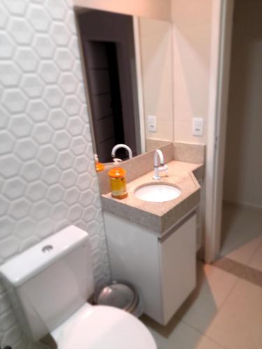ein Badezimmer mit einem WC, einem Waschbecken und einem Spiegel in der Unterkunft Flats Tavares Araujo in Garanhuns