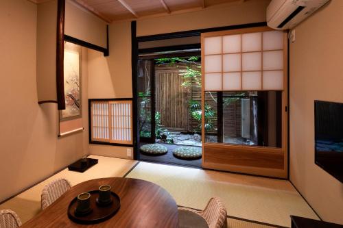 - un salon avec une table et une porte donnant sur un jardin dans l'établissement Rinn Tenjincho, à Kyoto