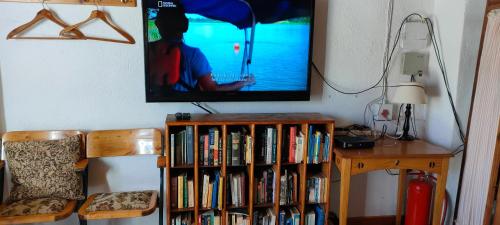 una televisione appesa a un muro con una libreria piena di libri di Den Hagen Guest Farm a Rhodes