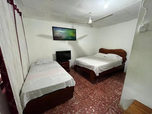 una piccola stanza con due letti e una tv di Cabinas Rhode island a Cahuita