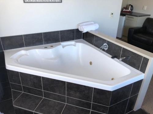 a large white bath tub in a bathroom at Absolute Lake View Motel in Taupo